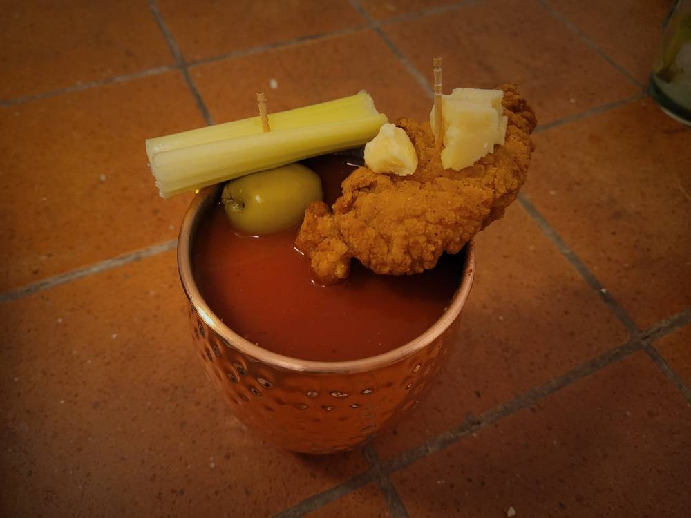 Picture of a virgin mary drink with olives, celery, and a chicken tender on it.